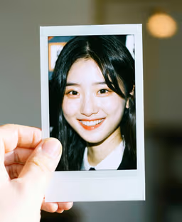 A photo of a polaroid portrait held in one hand, soft natural indoor light