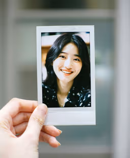 A smiling woman shown in a small instant photograph, photorealistic